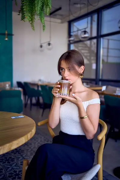 stock image 16-year-old teenage girl in old money style clothes drinks bumble coffee with an orange in  fancy restaurant