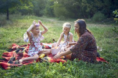 İki küçük kız ve anne Paskalya pikniğinde yumurta boyuyor.