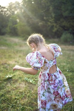 Çiçekli elbisesi ve Paskalya yumurtası avında sepeti olan küçük sarışın kız.