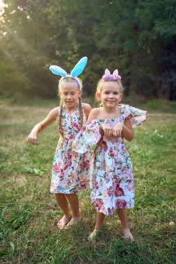 İki küçük kız, Paskalya yumurtası avında sarılıp tavşan oynuyorlar.