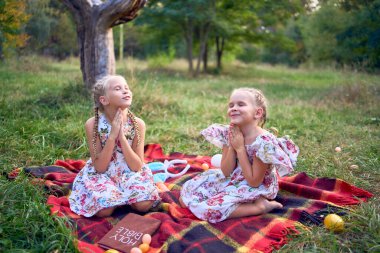 Küçük kızlar bahçede Paskalya pikniğinde Tanrı 'ya dua ederler.