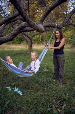          Anne ve küçük kızları birlikte hamakta oynuyorlar, çocuklarla kamp yapıyorlar.                      
