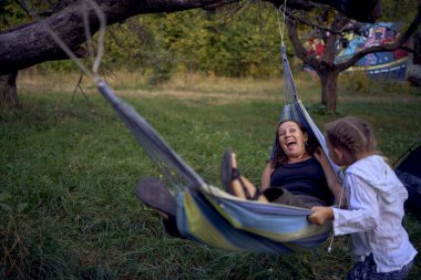          Anne ve küçük kızları birlikte hamakta oynuyorlar, çocuklarla kamp yapıyorlar.                      