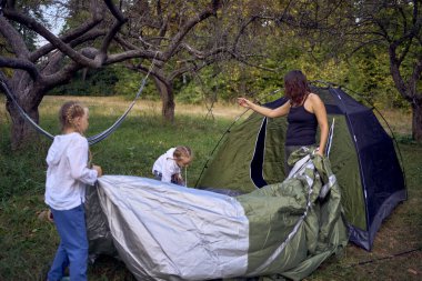              Anne ve küçük kızları ormanda bir çadır kuruyorlar, çocuklarla kamp yapıyorlar.                                                