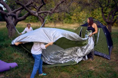               Anne ve küçük kızları ormanda bir çadır kuruyorlar, çocuklarla kamp yapıyorlar.                                                