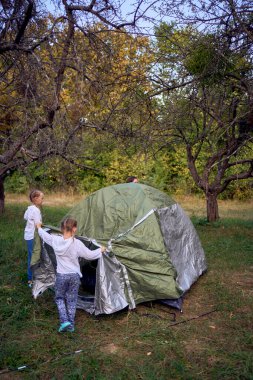               Anne ve küçük kızları ormanda bir çadır kuruyorlar, çocuklarla kamp yapıyorlar.                                                