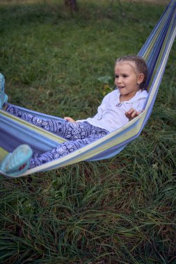 Küçük kız hamakta oynuyor, çocuklarla kamp yapıyor.                                             