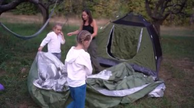 Anne ve küçük kızları ormanda bir çadır kuruyorlar, çocuklarla kamp yapıyorlar.