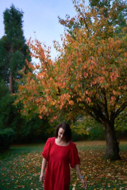       30 yaşında, orta boylu, sonbahar bahçesinde kırmızı çarşaf giymiş bir kadın.                        