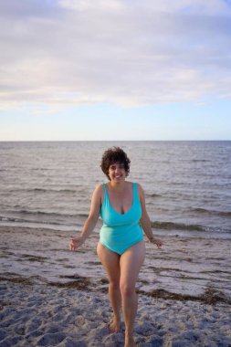  Genç, iri yarı bir kadın kışın yüzüyor ve deniz kenarında ısınıyor.                    