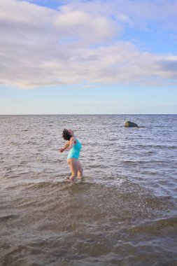  Genç, iri yarı bir kadın kışın yüzüyor ve deniz kenarında ısınıyor.                    