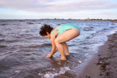  Genç, iri yarı bir kadın kışın yüzüyor ve deniz kenarında ısınıyor.                    