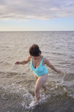  Genç, iri yarı bir kadın kışın yüzüyor ve deniz kenarında ısınıyor.                    