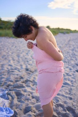 Genç ve iri bir kadın, kış denizi yüzüşünden sonra kıyafetlerini değiştirir.                           