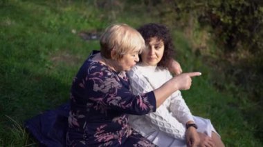 Orta yaşlı bir kız ve yaşlı bir anne birlikte sonbahar ormanında yürüyüş yapıyorlar.