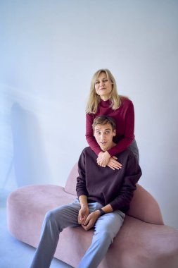 Orta yaşlı bir anne, yetişkin bir oğlanı kucaklıyor.                     