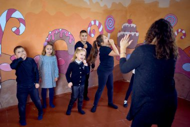 5-7 yaşlarındaki çocuklar oyunculuk sınıfında öğretmenleri ile ders dışı aktiviteler yapıyorlar.                      