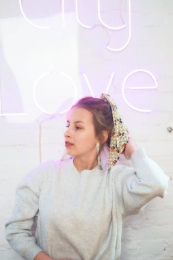 a portrait of a teenage girl near a white wall with a pink neon sign, studio photo session clipart