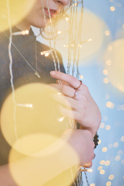 Девочка-подросток в платье в окружении золотых рождественских огней