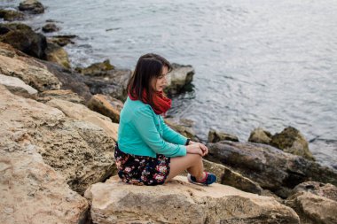 Kıbrıs Rum Kesimi Ayia Napa 'nın kayalık sahillerinde parlak elbiseli genç bir kadının portresi