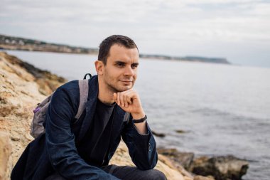 Kıbrıs Rum Kesimi 'nin kayalık Ayia Napa kıyısında sırt çantalı bir gencin portresi