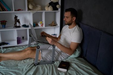 Elinde İncil olan 30 yaşında bir adam çevrimiçi bir kilise ayinine katılır ve papazla konuşur.