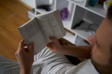 30 yaşında, elinde İncil olan bir adam çevrimiçi bir kilise ayinine katılıyor, papazla konuşuyor.                              