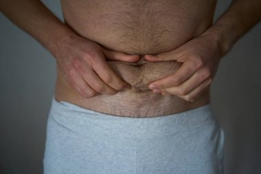  30 yaşında orta yapılı bir adam elleriyle deri ve yağ kıvrımlarını ovuyor.                          