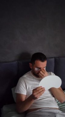 30 yaşında, uykusunda ipek maske takan, şişlik ve kırışıklıklardan dolayı gözlerinin altına yamalar takan bir adam.,