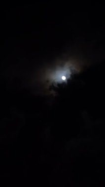 Gece gökyüzünde dolunay var. Fenerlerle aydınlatılmış gökdelenlerin üstünde.