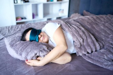          senior woman in silk eye mask sleeping under heavy blanket                       clipart