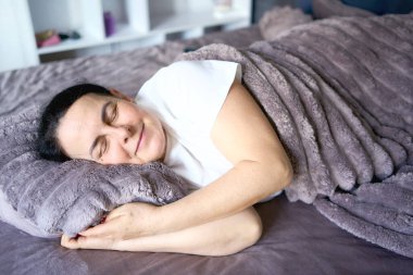          İpek göz maskeli yaşlı kadın ağır battaniyenin altında uyuyor.                      