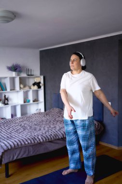       Son sınıf öğrencisi kadın somatik egzersizler yapıyor, evde yoga yapıyor kulaklıkla egzersiz müziği dinliyor.                         