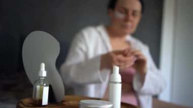 Yatakta iç çamaşırlı yaşlı bir kadın vücut kozmetikleriyle rutin bir kişisel bakım yapıyor.