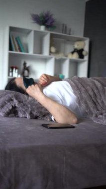 Son sınıf öğrencisi kadın yatakta telefonla konuşuyor.
