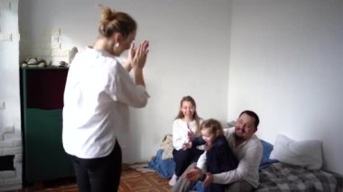 Bebekleri ve çocukları olan bir aile oyun oynuyor, gülüyor, alkışlıyor ve küçük bir aile partisini kutluyorlar.