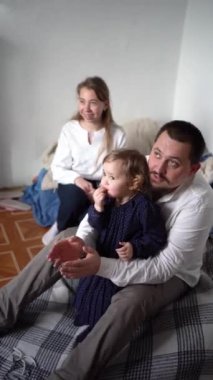 Bebekleri ve çocukları olan bir aile oyun oynuyor, gülüyor, alkışlıyor ve küçük bir aile partisini kutluyorlar.