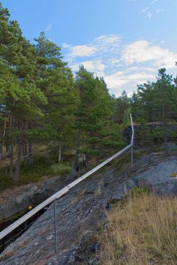 Landscape view of rocky forest on the island of Jussaro with handrail protecting open mine drift in summer, Raasepori, Finland.