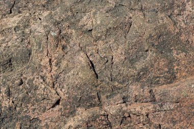 Arka planda çatlaklar olan pürüzsüz kaya dokusuna yakın çekim.