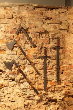 Ortaçağ silahlarının, kılıçların ve baltaların mahzendeki taş duvara yakın durması..