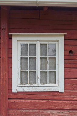 Eski kırmızı ahşap bir binanın beyaz çerçeveli penceresi..