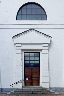 Kahverengi ahşap kapılı, penceresi beyaz taş basamaklı bir binanın üstünde..