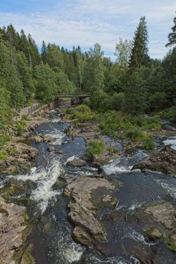 Vantaanjoki nehrinin yaz mevsiminde geçiş, kayalar, ağaçlar ve yapraklarla manzarası, Myllykoski, Nurmijarvi, Finlandiya.