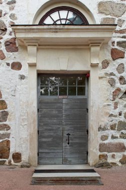 Taş bir binanın tepesinde penceresi olan eski ahşap kapı..