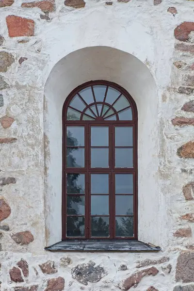 Kahverengi ahşap çerçeve bir pencere üzerinde kemer taştan bir bina.