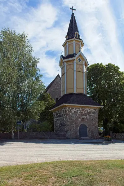 stock image Wooden bell tower of old stone Pertteli church in summer with clouds in the sky, Pertteli, Finland.