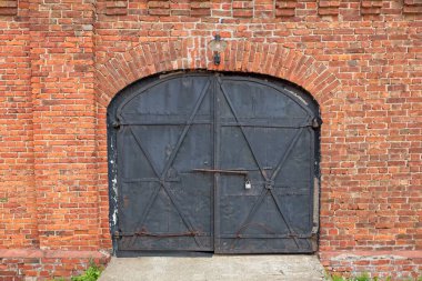 Kırmızı tuğlalı kemerli eski siyah metal kapı..