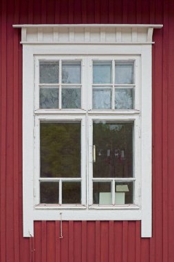 Eski kırmızı ahşap duvarın beyaz çerçeveli penceresi.