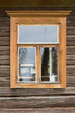 Eski kütük duvarındaki açık kahverengi çerçeveli pencere.