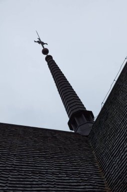 Bulutlu sonbahar havasında haçlı kilise kulesinin silueti..
